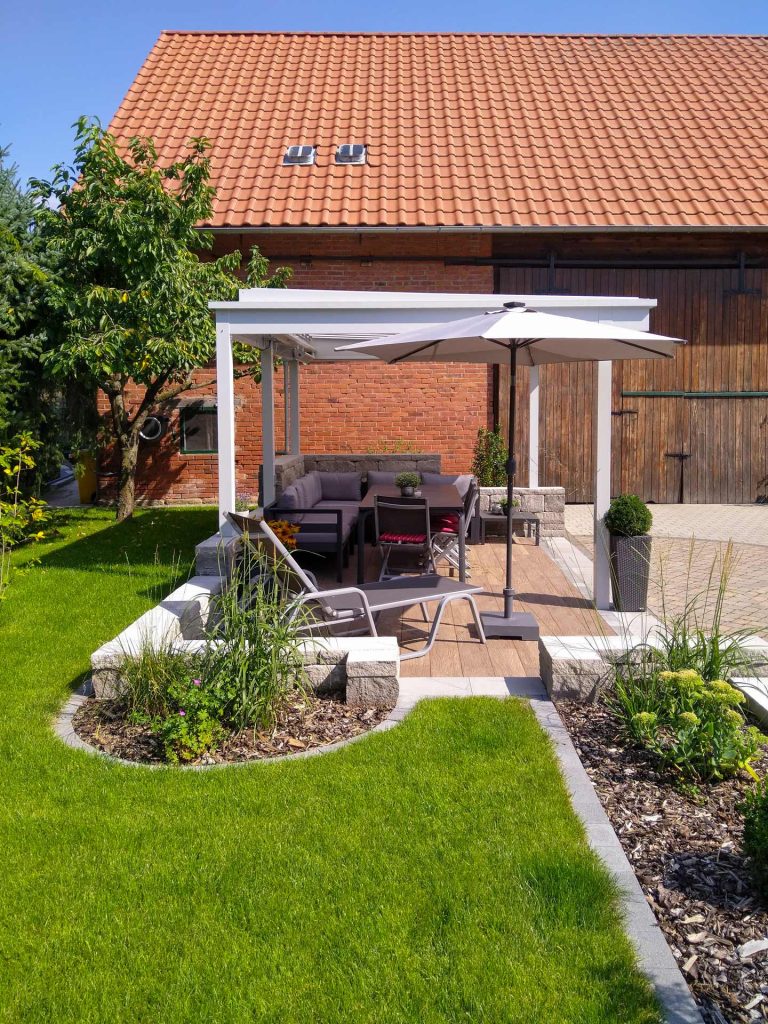 Gartengestaltung mit überdachter Sitzveranda, erstellt von der Firma Aussengestaltung Vogt