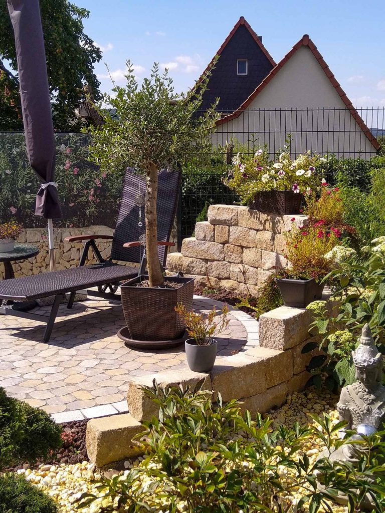 ringförmige Gartenmauer und Pflasterung enes Sitzbereichs, erstellt von der Firma Aussengestaltung Vogt