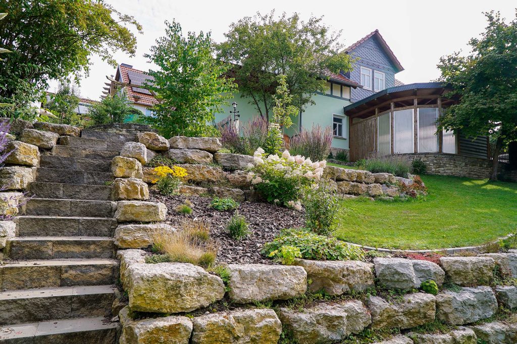 Gartentreppe aus Naturstein mit niedrigen Gartenmauern, erstellt von der Firma Aussengestaltung Vogt
